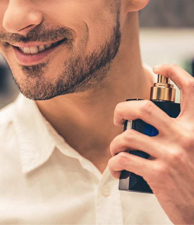 Handsome guy is choosing perfumes and smiling while doing shopping in the mall