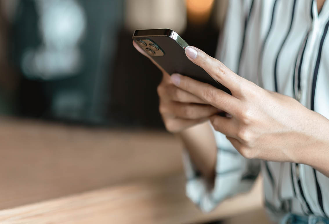 Close up hand of woman using smartphone at coffee shop cafe.