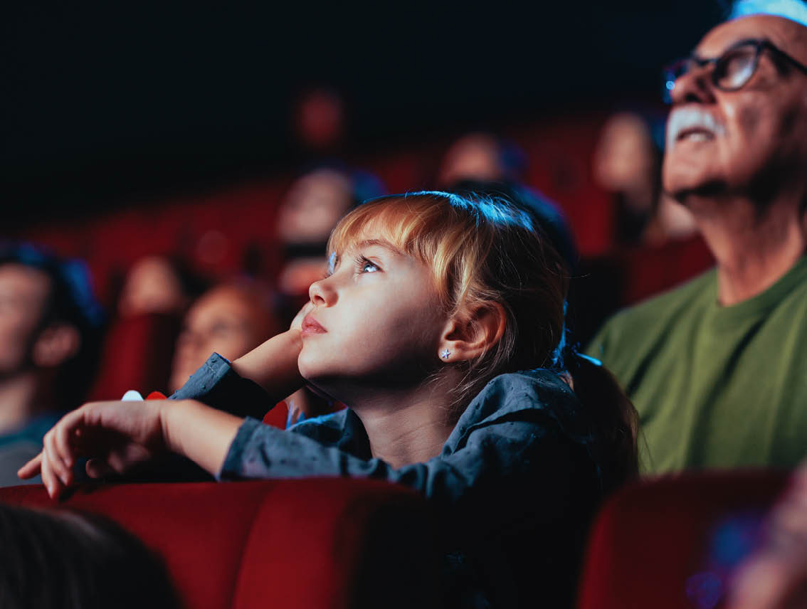 A senior man and his granddaughter are in the cinema watching a movie together and bonding.