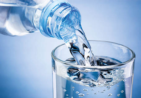 Pouring water from bottle into glass on blue background / Bouteille d'eau en plastique et verre d'eau sur fond bleu