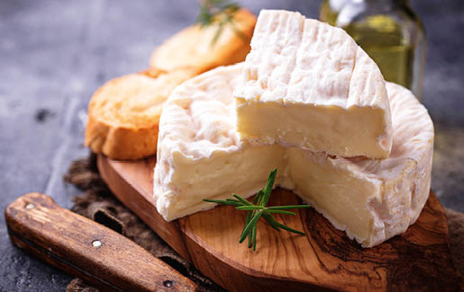 Camembert cheese with rosemary on wooden board. Selective focus