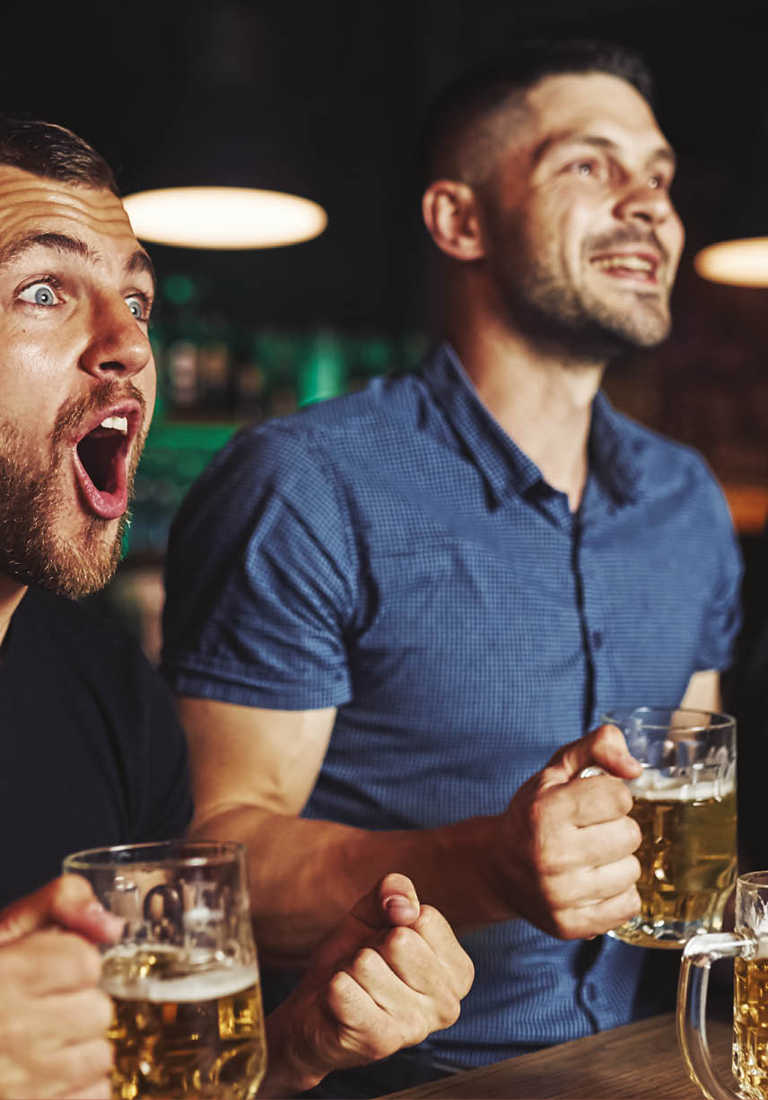 Celebrating victory. Three sports fans in a bar watching soccer. With beer in hands.